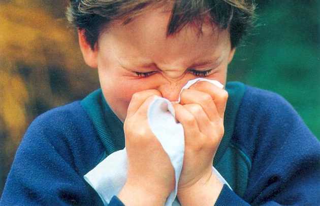boy with a sinus infection blowing his nose
