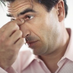 Man with a Sinus Infection holding top of his nose between eyes