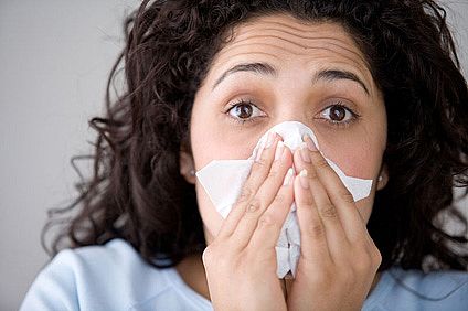 Woman with flu symptoms blowing her nose