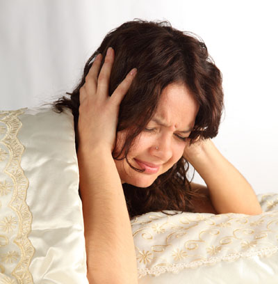 girl in bed showing signs of anxiety by clenching her head with her hands