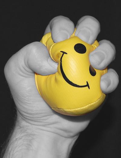 hand clenching and stressing a yellow happy face